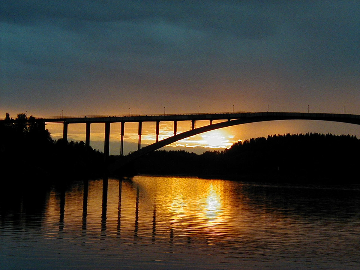 Sandöbron i solnedgång, bilden är mörk och orange.