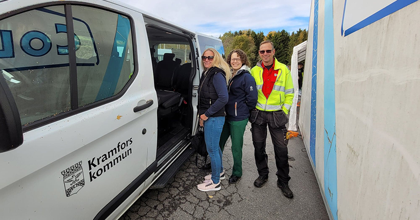 3 personer på väg in i en vit minibuss med Kramfors kommuns logotype.