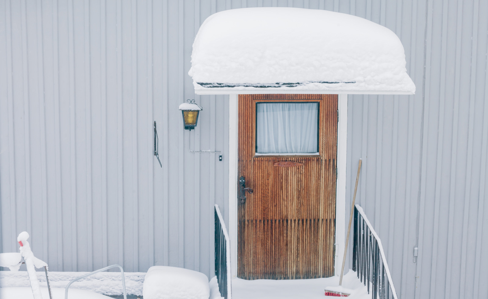 Skärmtak över ytterdörr på en villa med tjock laget snö på