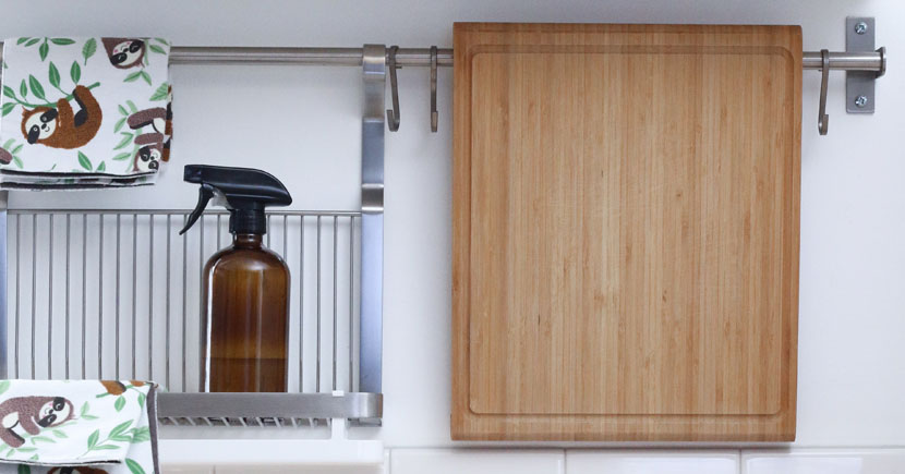 En detaljbild från ett kök föreställande en skärbräda, ett diskställ och en sprayflaska innehållandes rengöringsmedel.