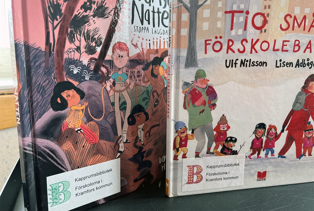 Två böcker som visar de särskilda klistermärken med information om att böckerna tillhör kapprumsbiblioteken i Kramfors.