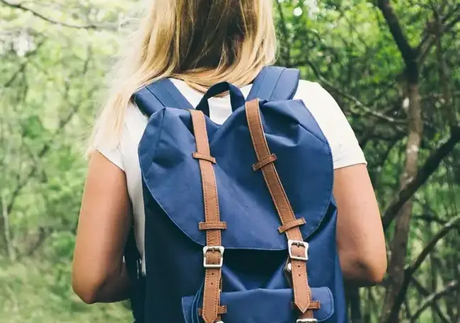 Person som går i skogen med en blå ryggsäck