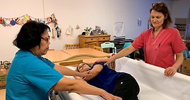 Två undersköterskor visar hur man vänder en person med motoriserat draglakan.